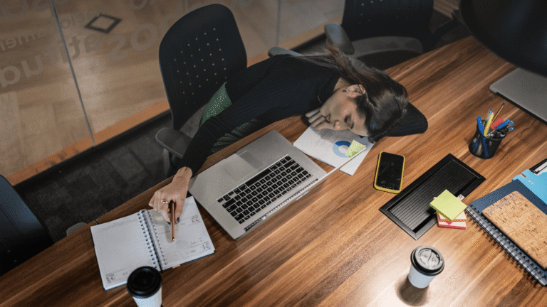 Eine Frau liegt auf dem Schreibtisch und macht einen Stealth Nap (Power Nap)